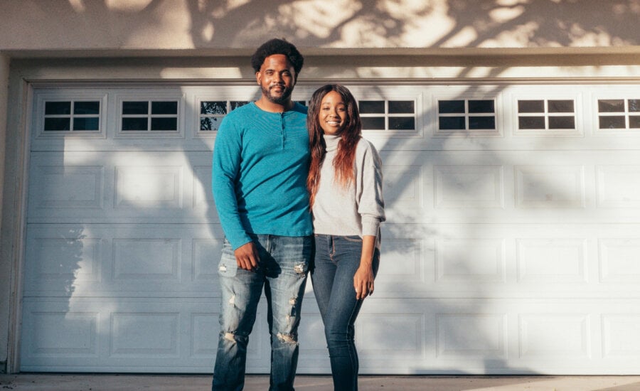 Canadian couple outside their home, wondering about the cost of their mortgage payments and if they will rise.