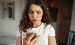 A young woman frowns as she checks her banking app