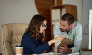 A Canadian woman and man looking at income statements to prepare their taxes for a tariff war.