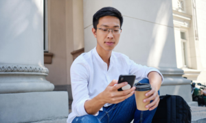 A young man checks his investment portfolio on his phone